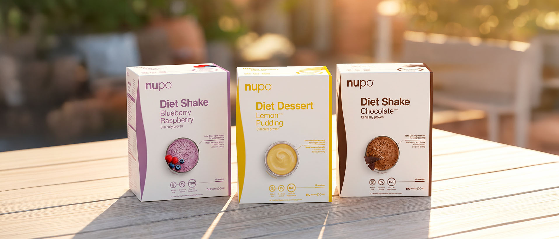 Three Nupo diet products displayed: Blueberry Raspberry shake, Lemon Pudding dessert, and Chocolate shake.